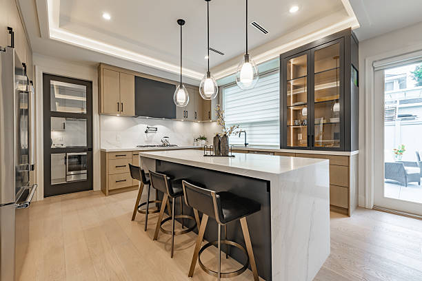 Kitchen interior with bar stools white countertops wooden cabinets pendant lighting extra kitchen sink glass cabinets hardwood floors stainless steel appliances window with coverings blinds drawn